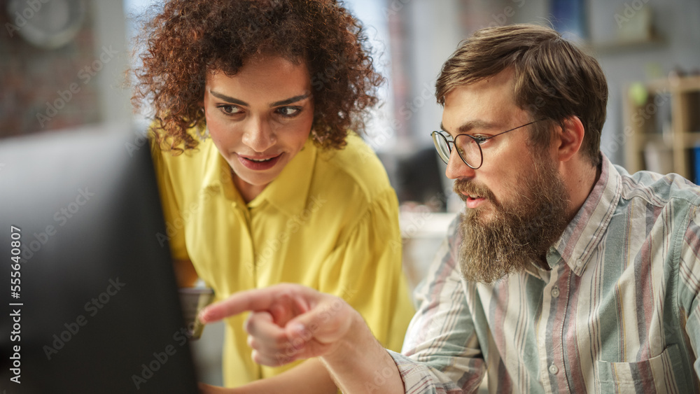 Fototapete Young Multiethnic Creative Team Brainstorming and Problem Solving, Using Computers in Modern Office During the Day. Biracial Woman Strategizing with Caucasian Male Colleague.