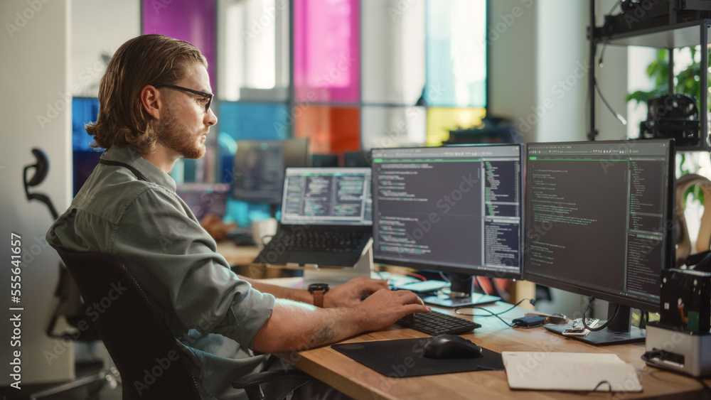 Leinwandbilder Male Programmer Using Desktop Computer And Laptop To Write Code In Creative Office. Caucasian Man Using Multiple Displays Set Up. Developing Software As A Service Platform For Innovative Start-Up.
