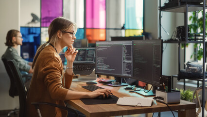 Caucasian Woman Writes Lines of Code on Desktop PC with Multiple Displays and a Laptop in Stylish...