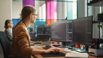 Female Software Engineer Writing Code on Desktop Computer with Multiple Screens Setup in Stylish...