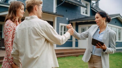 Happy Real Estate Agent Congratulating Young Homeowners with Their New Home Acquisition. Cheerful Couple Shaking Hands with the Businesswoman and Receiving Keys From Their Property.