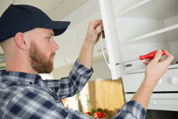 man fitting handle on a kitchen cupboard