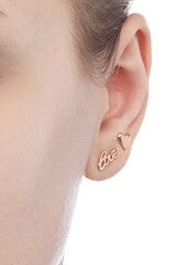 isolated on white background jewelry gold earrings stud with heart LOVE and shadow. On the arm and ears of a female model.