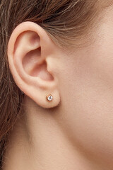isolated on white background jewelry gold and silver stud earrings with shadow. Dressed on the ears of a girl model.