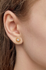 isolated on white background jewelry gold and silver stud earrings with shadow. Dressed on the ears of a girl model.