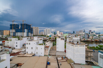 Fototapeta premium HO CHI MINH, VIETNAM - December 3, 2022: Slum wooden house on the Saigon river bank, in front of modern buildings in ho chi minh city. View to district 1, see Bitexco tower, Landmark 81.
