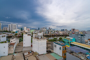 Fototapeta premium HO CHI MINH, VIETNAM - December 3, 2022: Slum wooden house on the Saigon river bank, in front of modern buildings in ho chi minh city. View to district 1, see Bitexco tower, Landmark 81.