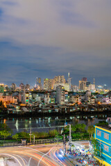 Obraz premium HO CHI MINH, VIETNAM - December 3, 2022: Slum wooden house on the Saigon river bank, in front of modern buildings at night in ho chi minh city. View to district 1, see Bitexco tower, Landmark 81.