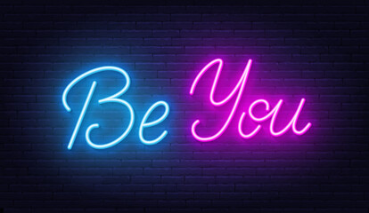Be You neon quote on brick wall background.
