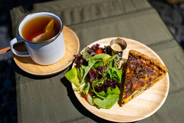 Slice of tart with chicken and mushrooms with salad on dish in coffee shop