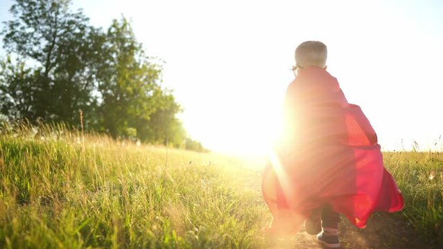baby superhero run. happy family kid dream concept. a small child in a mask and a red raincoat runs along the path in nature in the park plays a superhero. top dreamer baby fun run