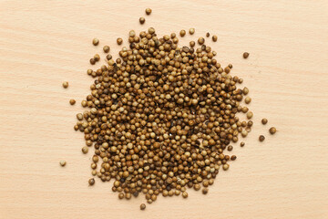 Pile of roasted coriander seeds isolated on brown wooden background