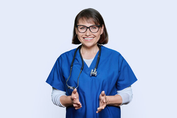 Portrait of middle aged doctor in uniform looking at camera on white background