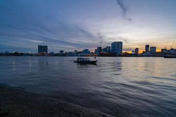 Naklejka premium Ho Chi Minh City skyline and the Saigon River at sunset. Amazing colorful view of skyscraper and other modern buildings. Travel concept
