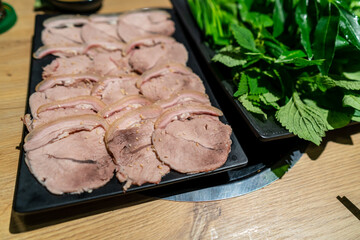 boiled pork belly with rice paer and green vegetables in a plate. A familiar dish in Vietnamese families