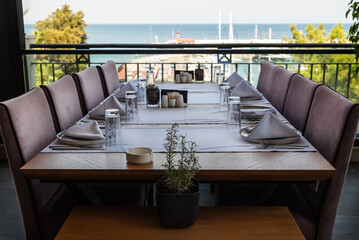 Dinner setting at harborside restaurant with sea harbor and yachts in background: moody and romantic