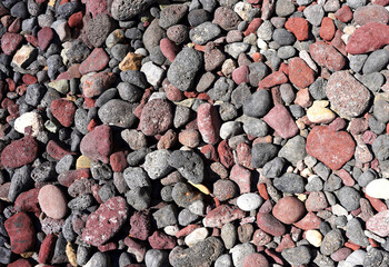 Small red, black, grey, white stones of seashore as nature background. Rock texture.