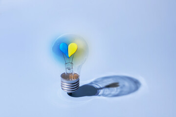 The glass bulb lamp with a heart in yellow-blue Ukrainian colors glows inside. Strong concept of...