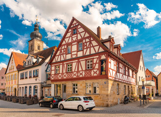 Obraz premium Sattlertorstrasse with old historic traditional German half timbered houses and St Martin church tower in the background with blue sky, Forchheim, Germany