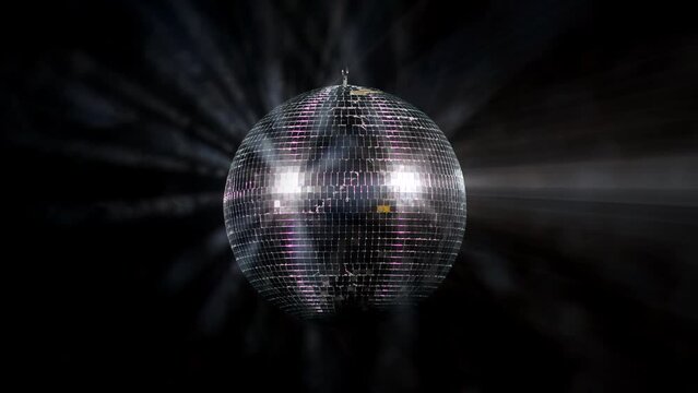 Disco Ball with Reflected Moving Rays Rotating. Mirror disco ball in white light. Isolated disco ball on black background. Close-up. Mirror ball spinning indoors. Performance. The reflection of lights