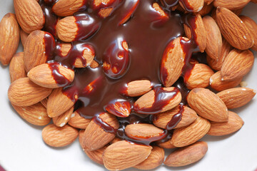 dark chocolate cream pouring on almond nut on white 