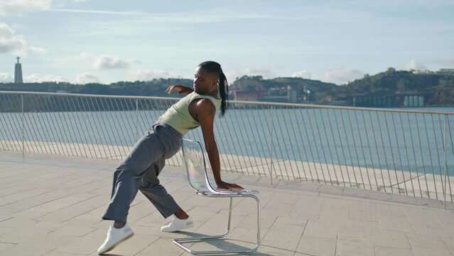 Flexible performer dancing chair on sea embankment. Dancer practice choreography