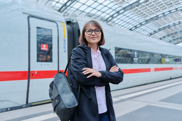 Woman passenger on railway platform inside station, with crossed arms looking at camera