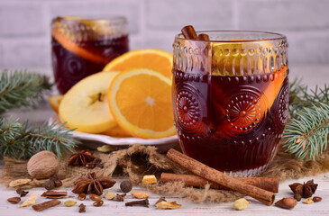 Christmas mulled red wine with spices and fruits on a wooden rustic table. Traditional hot drink at Christmas time
