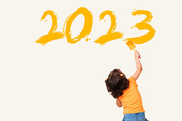 Fototapeta Cute little girl drawing new year 2023 with painting brush on wall background obraz