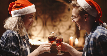 Caucasian couple sitting on floor of decorated room, drinking red wine from glasses, spending christmas eve together - holidays and celebrations, christmas spirit concept 
