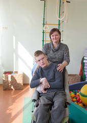 a boy with a disability in a rehabilitation center with special needs next to his mother.