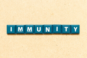 Tile alphabet letter in word immunity on wood background