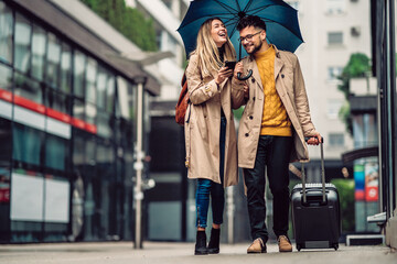 beautiful smiling young couple walking in the rain - obrazy, fototapety, plakaty