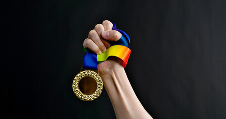 Human hand holding gold medal on black background