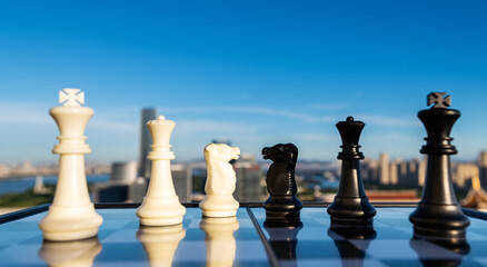 Black and white chess pieces on city background