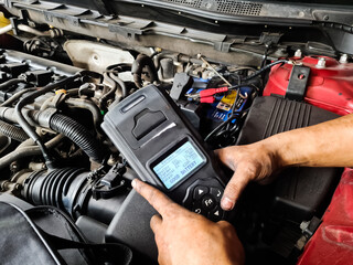 Engineer holding Handheld device for Check up car battery life. battery tester concept.