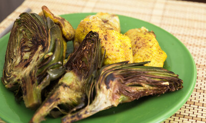 cooked fried chicken wings and halves artichokes on green plate