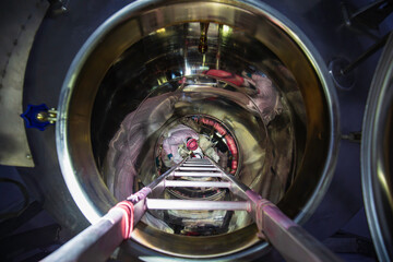 Inside male worker into the inspection shiny tank stainless chemical area confined space