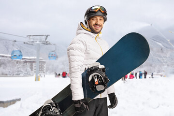 Snowboarder holding a snowboard in front of a ski lift