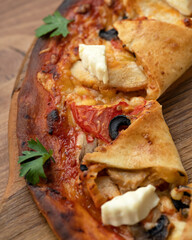 Italian pizza with cheese, tomatoes, sauce on wooden board. Italian food. Creative pizza serving. Wooden background. Close-up. Soft focus. Top view