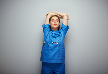 Nurse woman in blue medical suit standing with hands raised up. Isolated portrait of chilling medical worker.