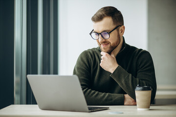 Young business man working on computer aqnd drinking coffee at the office
