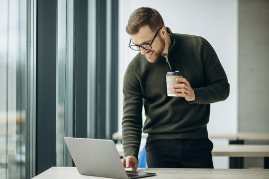 Young business man working on computer aqnd drinking coffee at the office