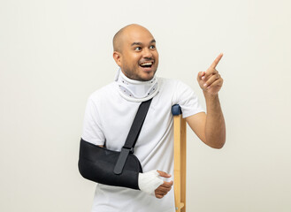 Shocked face man broken arm and leg pointing finger to blank space. Man put on plaster cast splint...