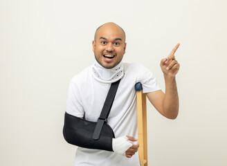 Shocked face man broken arm and leg pointing finger to blank space. Man put on plaster cast splint...