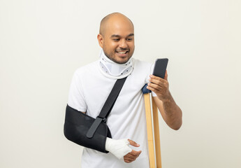 Happy young asian man broken arm holding smartphone. Asian man put on plaster bandage cast splint....