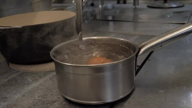 Cuisinier met un oeuf dans la casserole