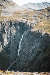 Waterfall at the trollstigen road in Norway with some mountains.