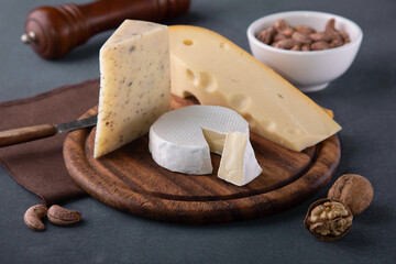 various types of cheese with nuts on dark grey background