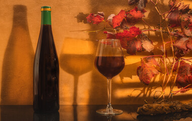 	
Verre de vin rouge avec une bouteille de vin sans étiquette avec en arrière plan des feuilles...